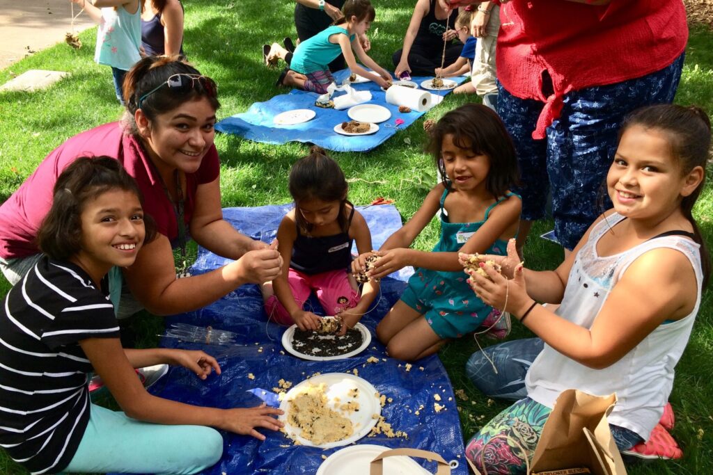 mother and four children crafting on a tarp outside