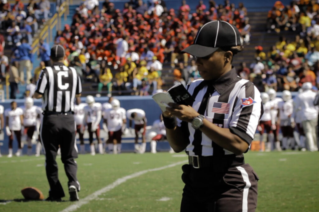 female referee writing in a notepad on a football field