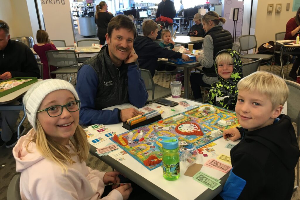 father and two children crafting at a table in a library