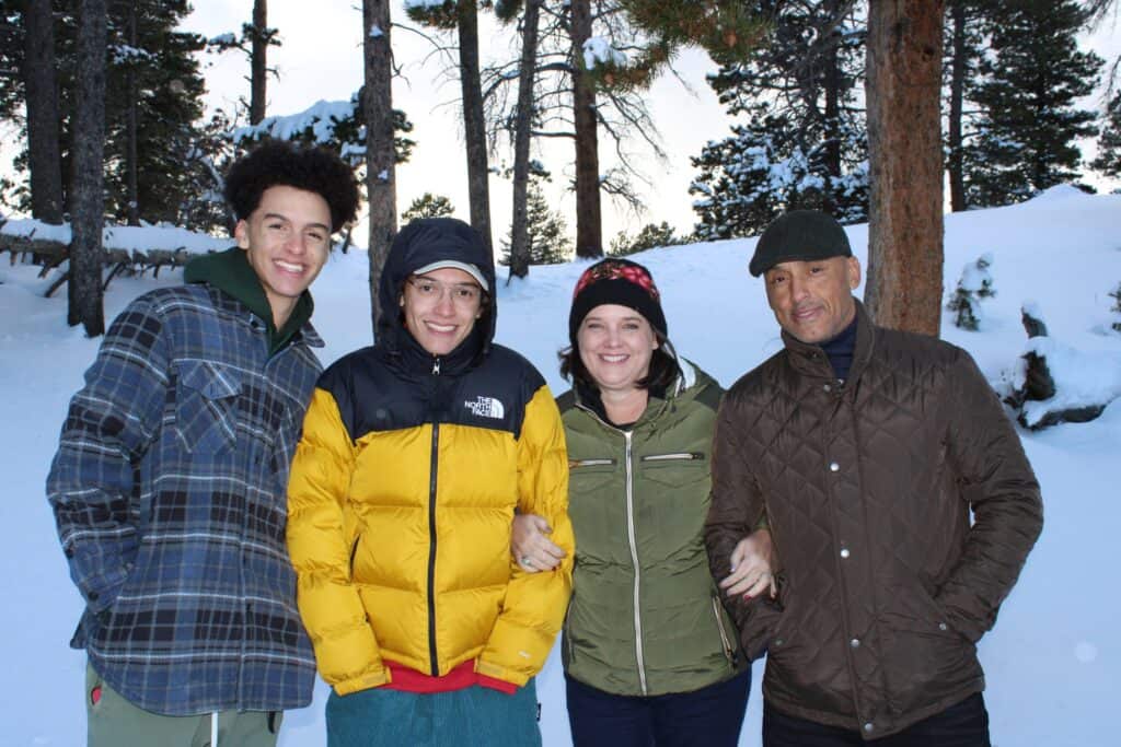 parents with their two sons smiling for a photo in the snow