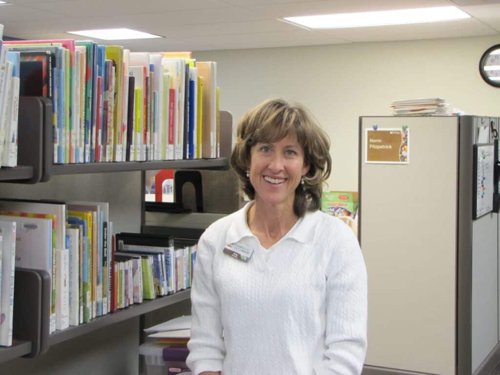 woman in front of bookshelves smiling for a photo