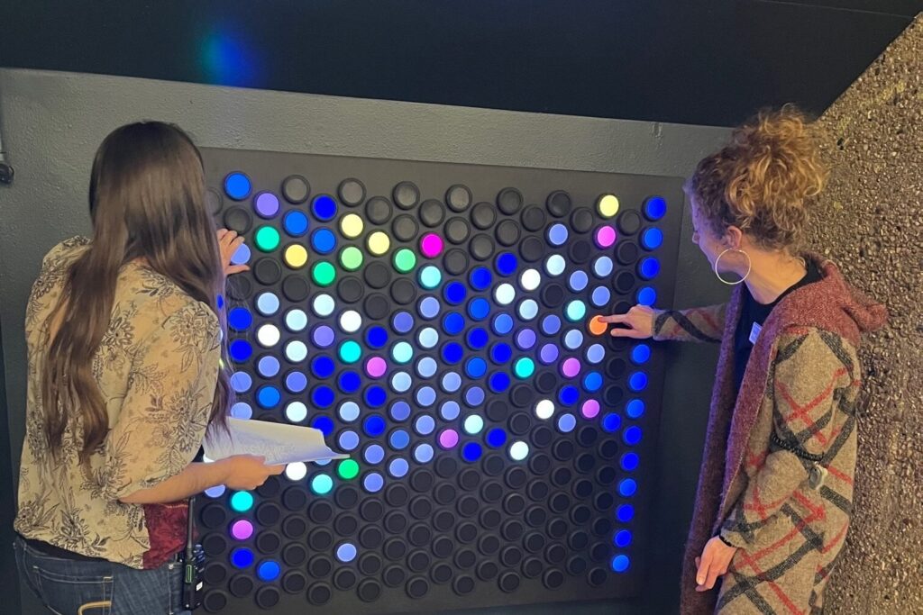 two women playing with a light installation on a wall