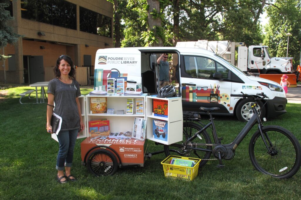 woman smiling next a bike that delivers books