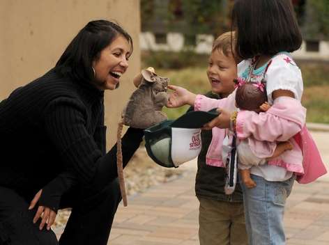 woman showing two young children a puppet