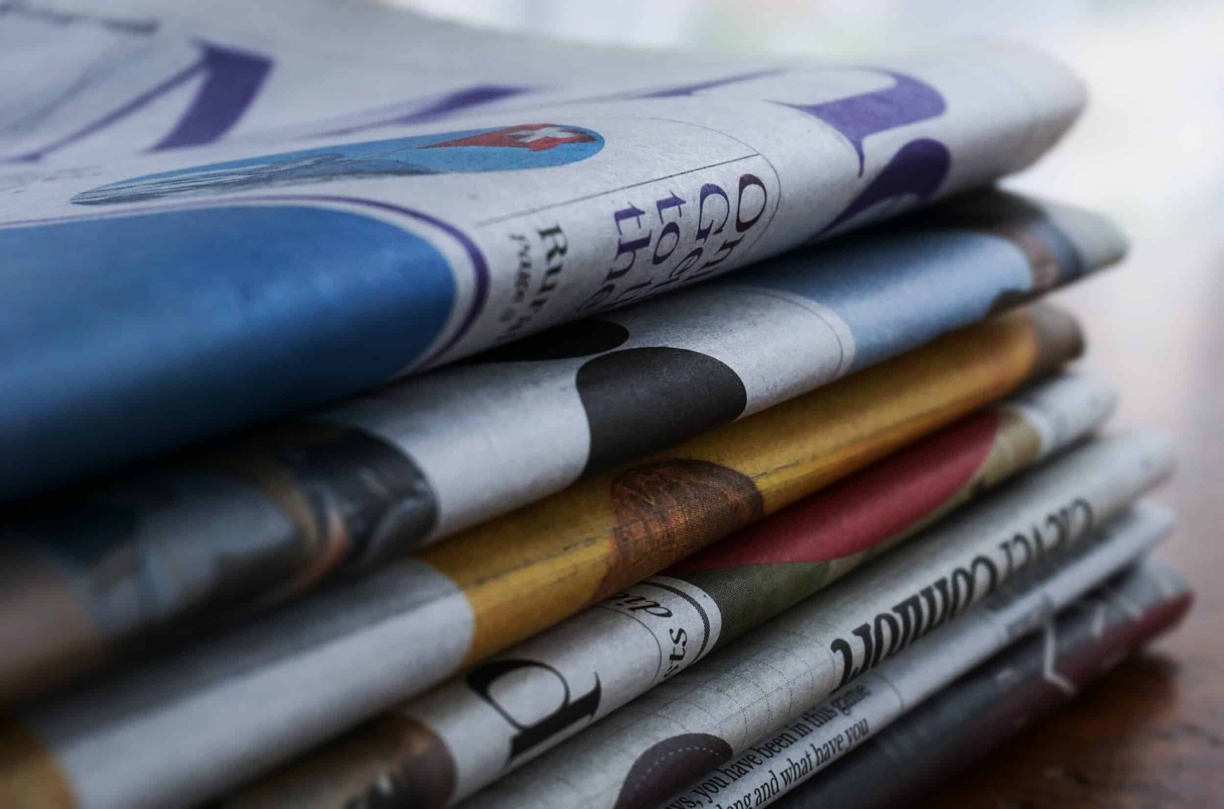 Varios periódicos apilados sobre una mesa.