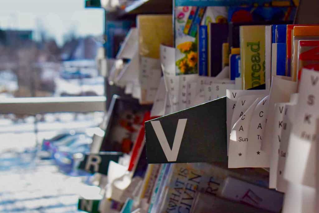 A hold section of a library with various shelved books that have printed receipts in them