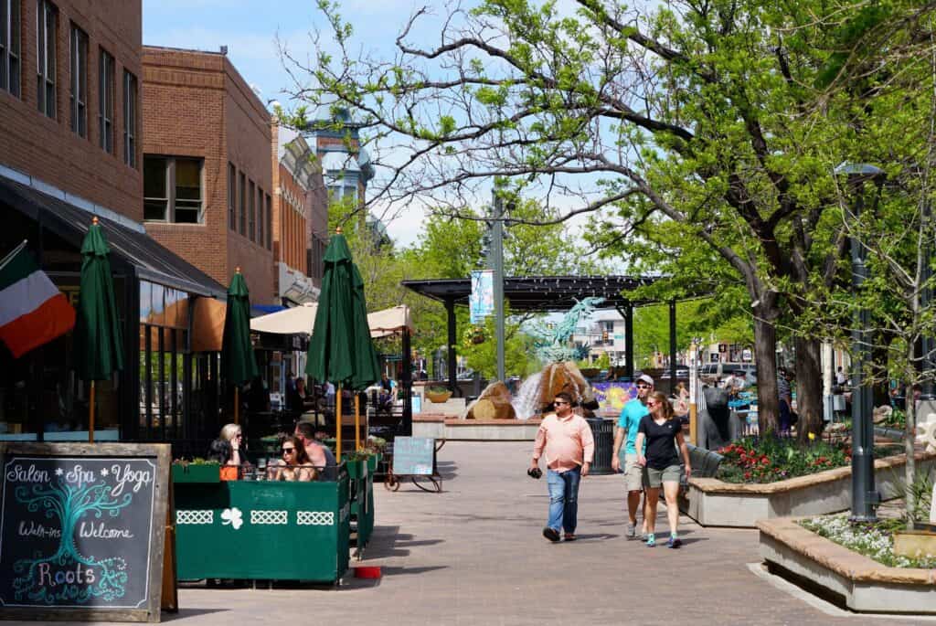 Three people strolling down the sidewalk in Old Town Square, Fort Collins