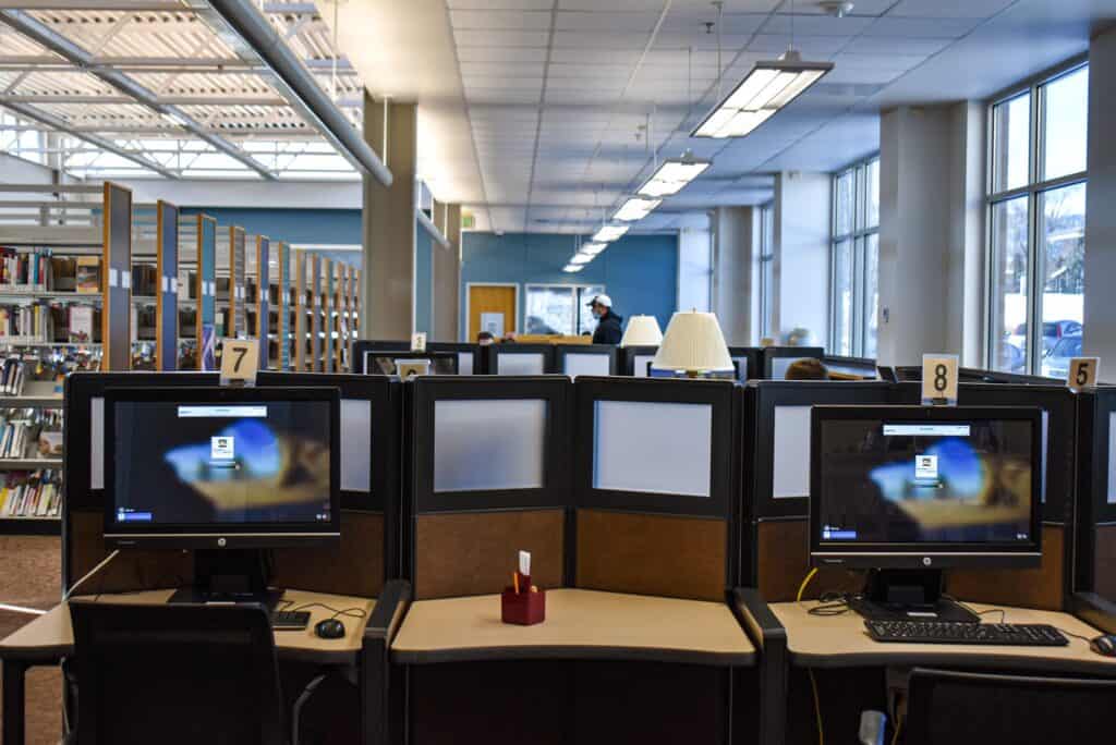 Desktop computers on desks with chairs in front of them at a library