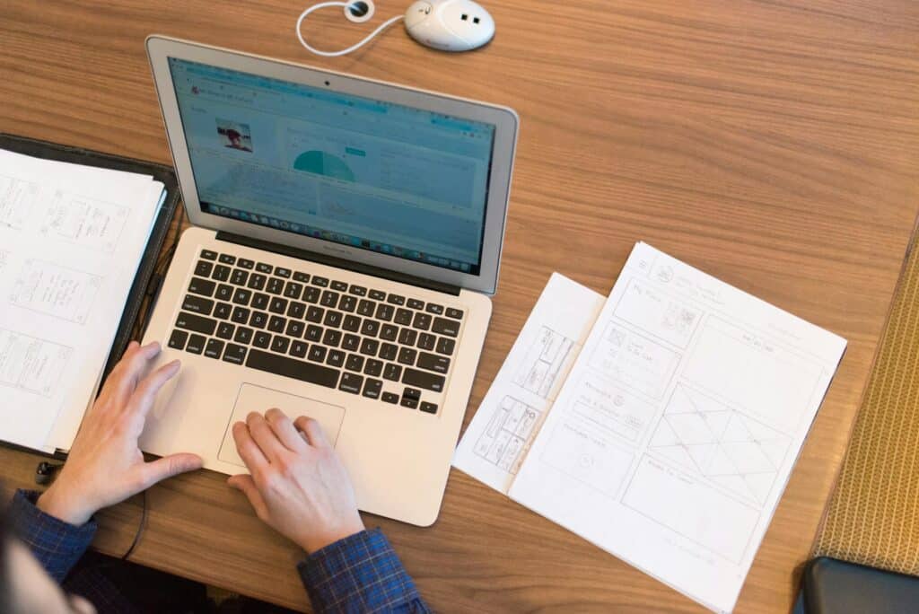 Hands of a person on a laptop with an open screen displaying graphs