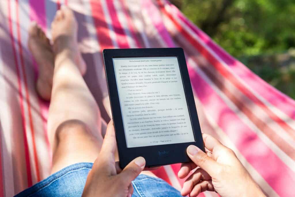 Legs of a woman in pink hammock holding an e-reader