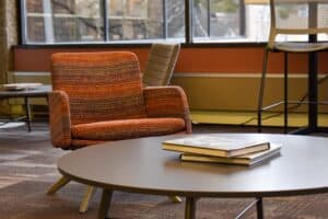 Upholstered red and cream chair in front of a low-to-the-ground grey table with two hardcover books on it.