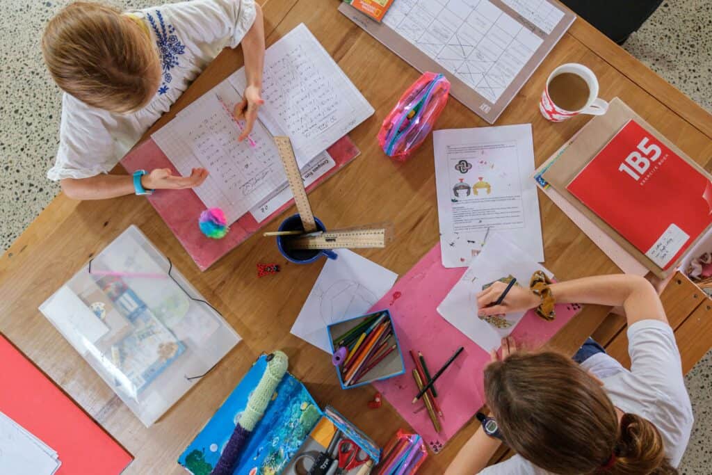 Two young girls filling out worksheets on a table