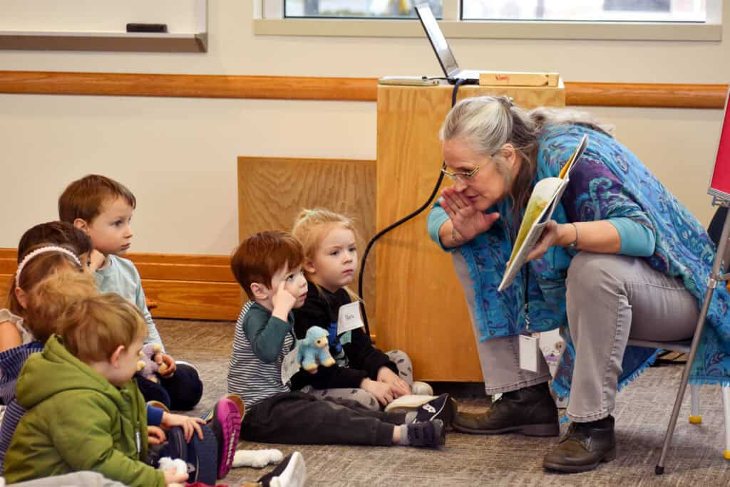 Older woman reading a book to a group of children