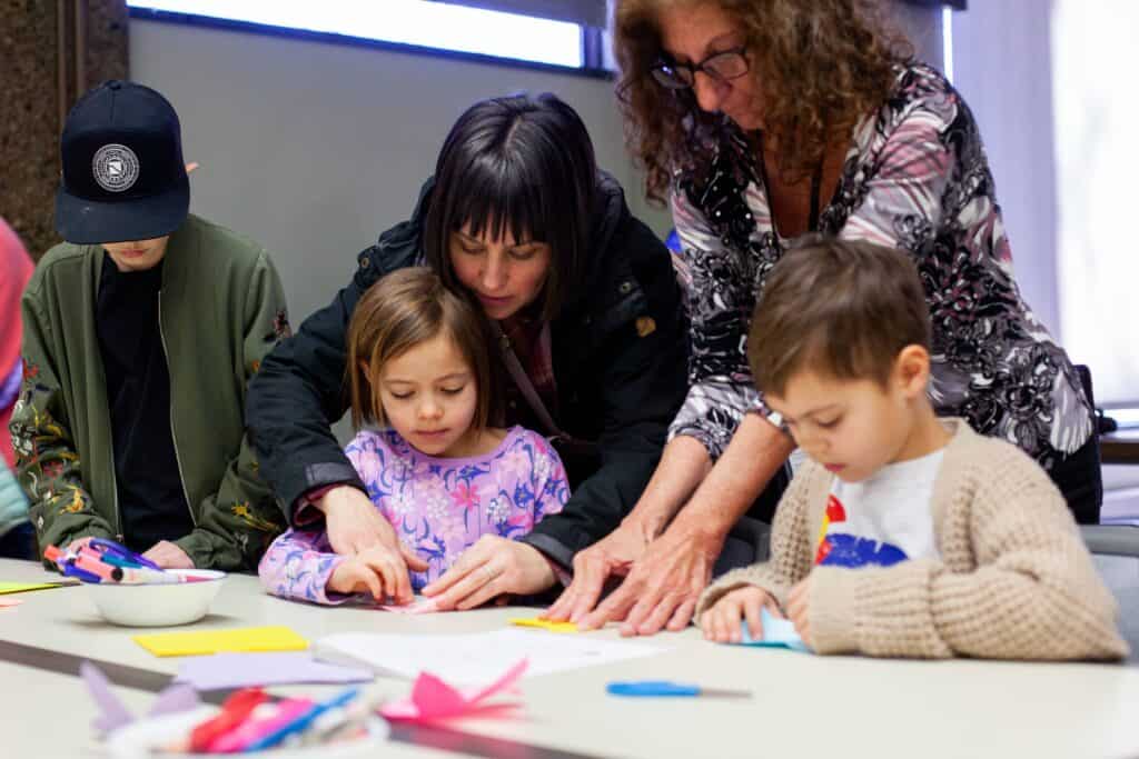 Two women, two young boys, and one one girl completing a craft together.