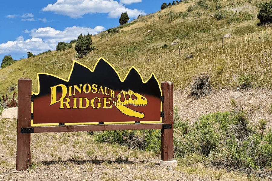 Sign at the bottom of a grassy hill reading Dinosaur Ridge