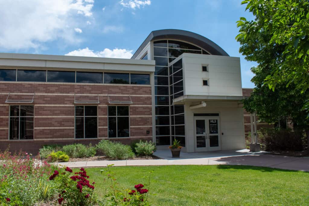 Exterior of Harmony Library with a green lawn and foliage around the building