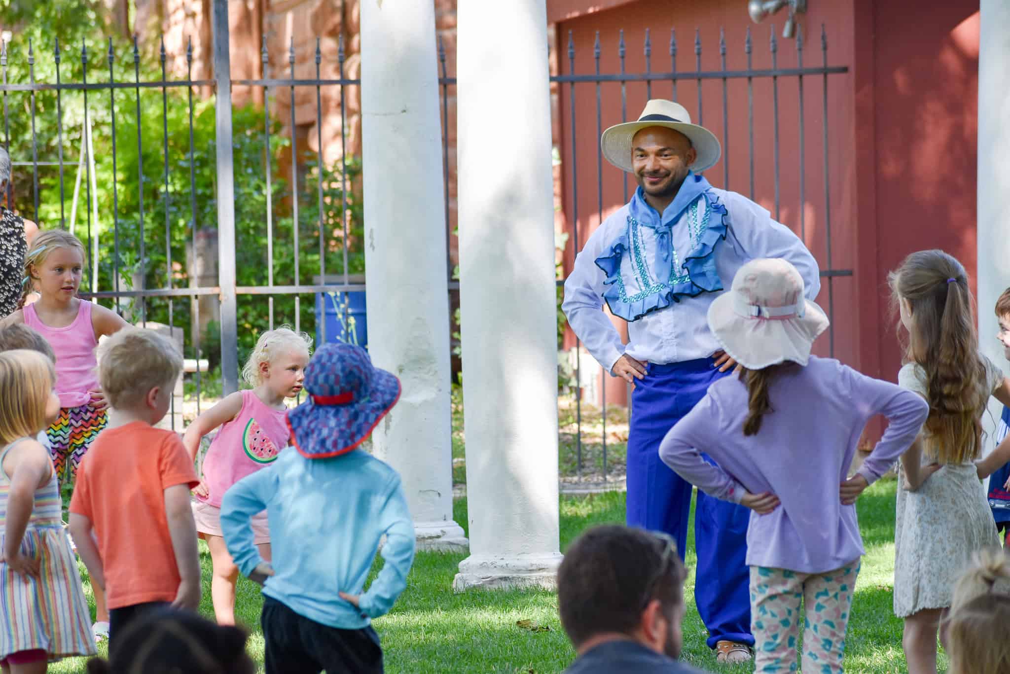 Man leading a dance with various children outside