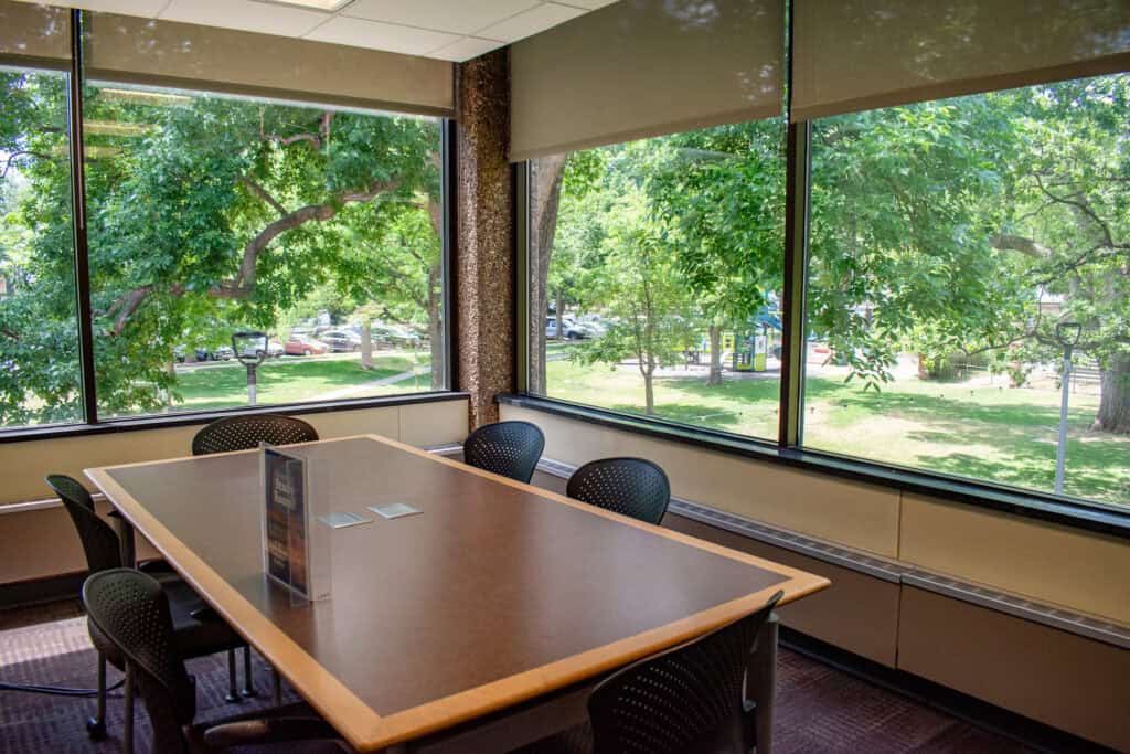 Medium-sized study room with two large windows facing a park with trees