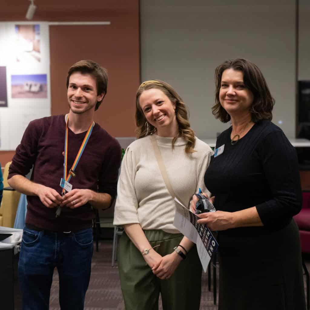 Two women and a man smiling for a photo inside a library