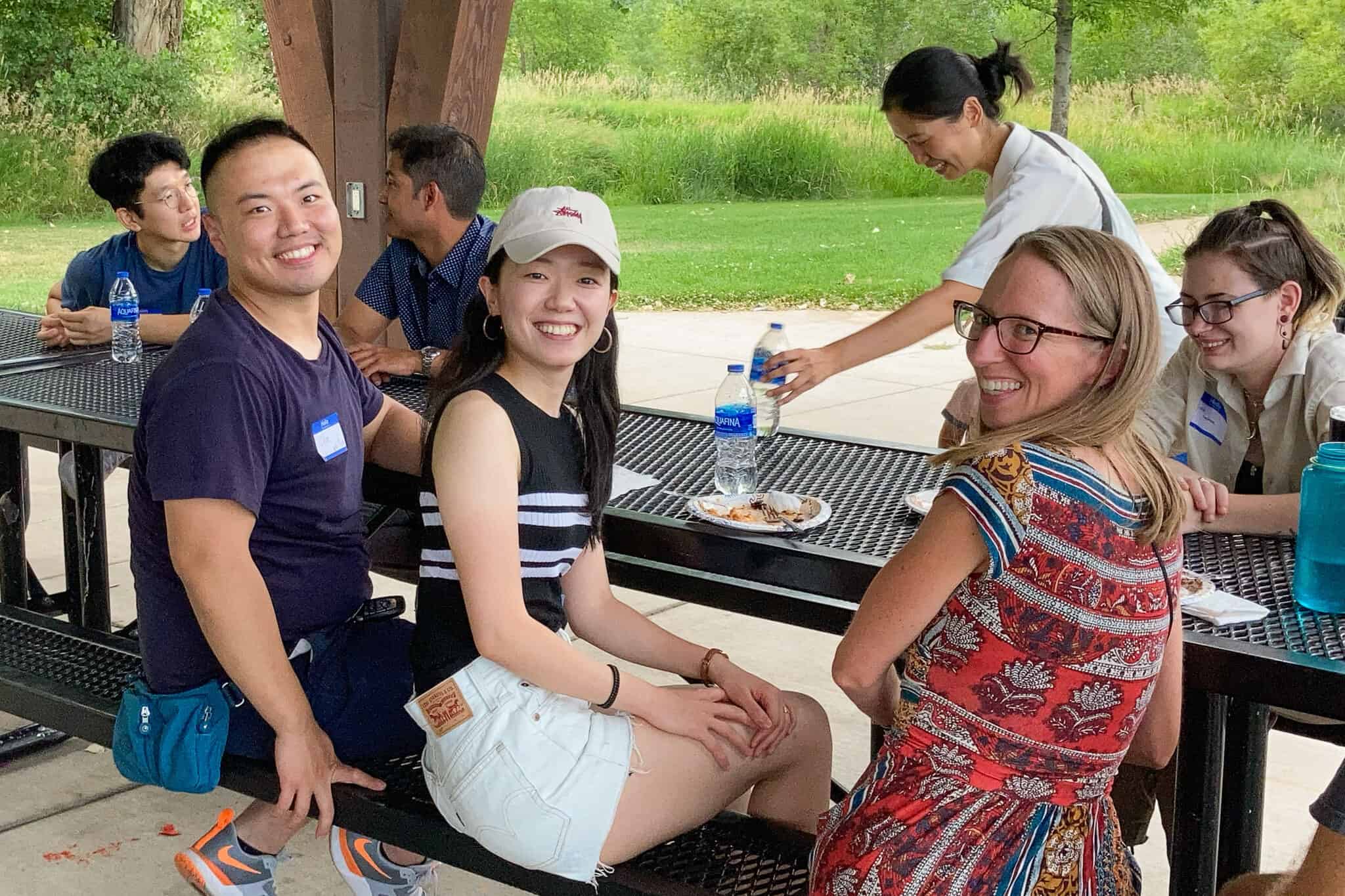 Dos mujeres y un hombre sonriendo para una foto en la mesa de un parque