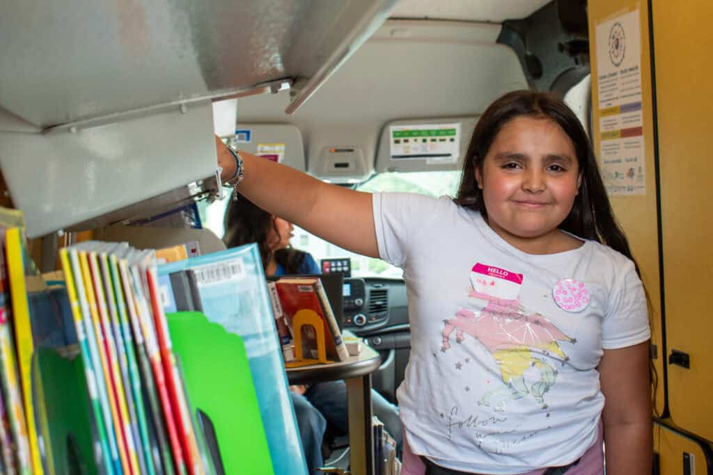 Young girl smiling for a photo inside a library bookmobile