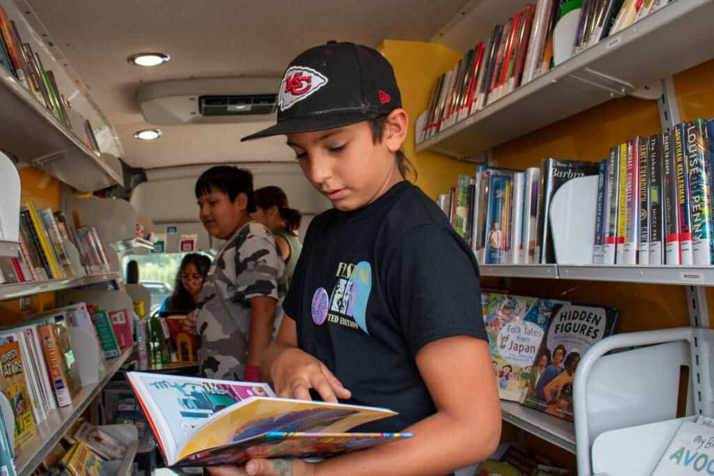 Young boy reading a book inside of "Evie," the library bookmobile