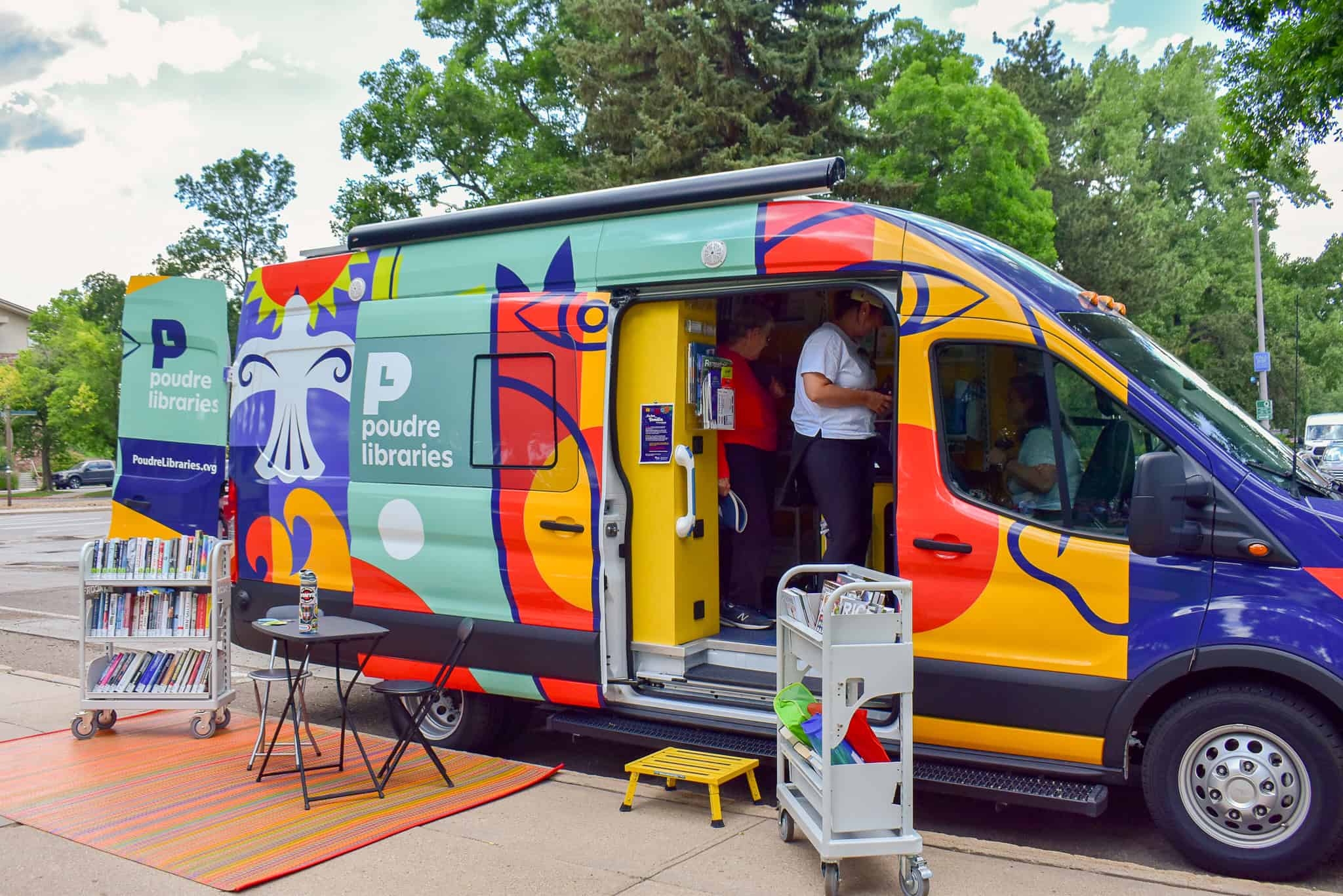 Evie the Mobile Library, a colorful van, parked while patrons browse the collection