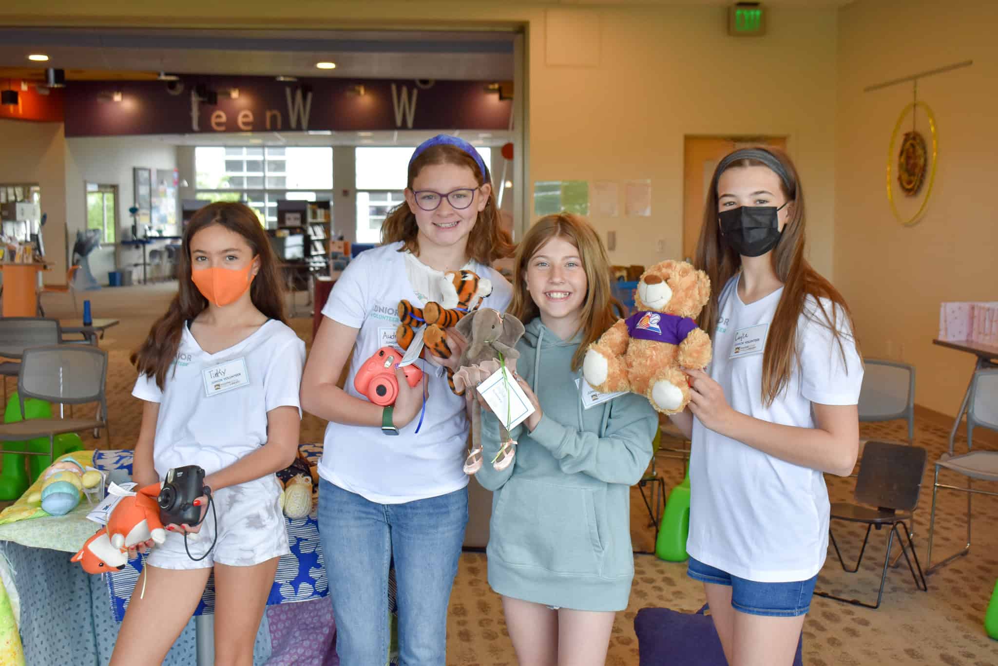 Four young junior volunteers holding stuffed animals