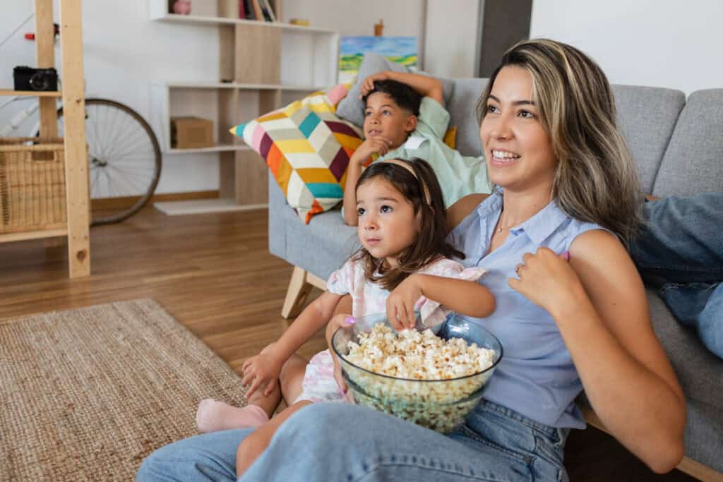 Mujer joven con dos niños pequeños disfrutando de una película