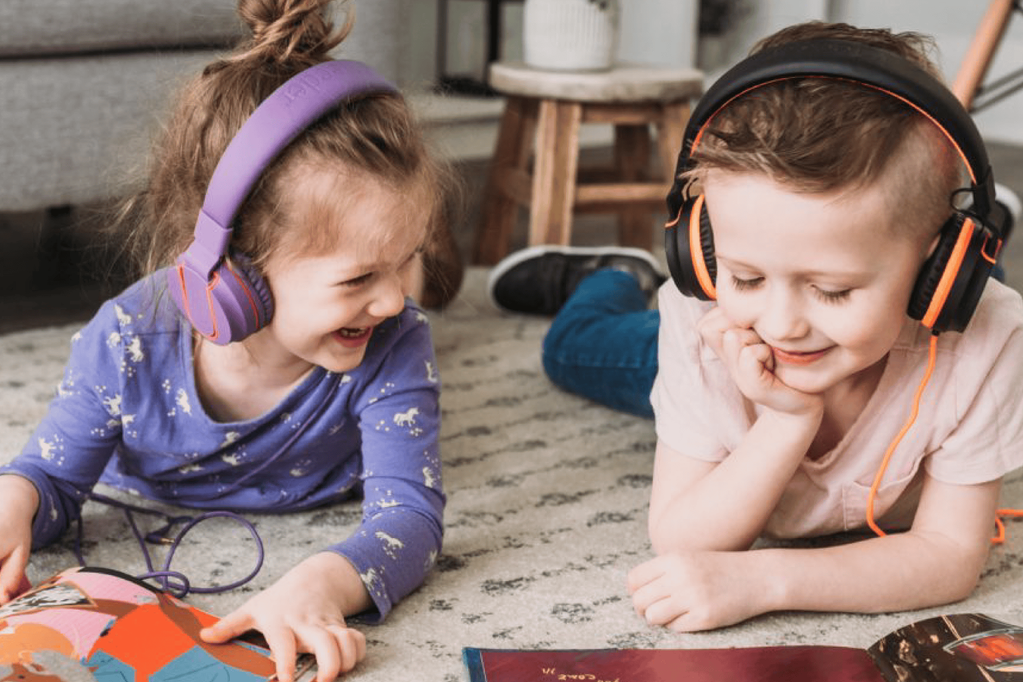 Two young children wearing headphones while reading playaway books