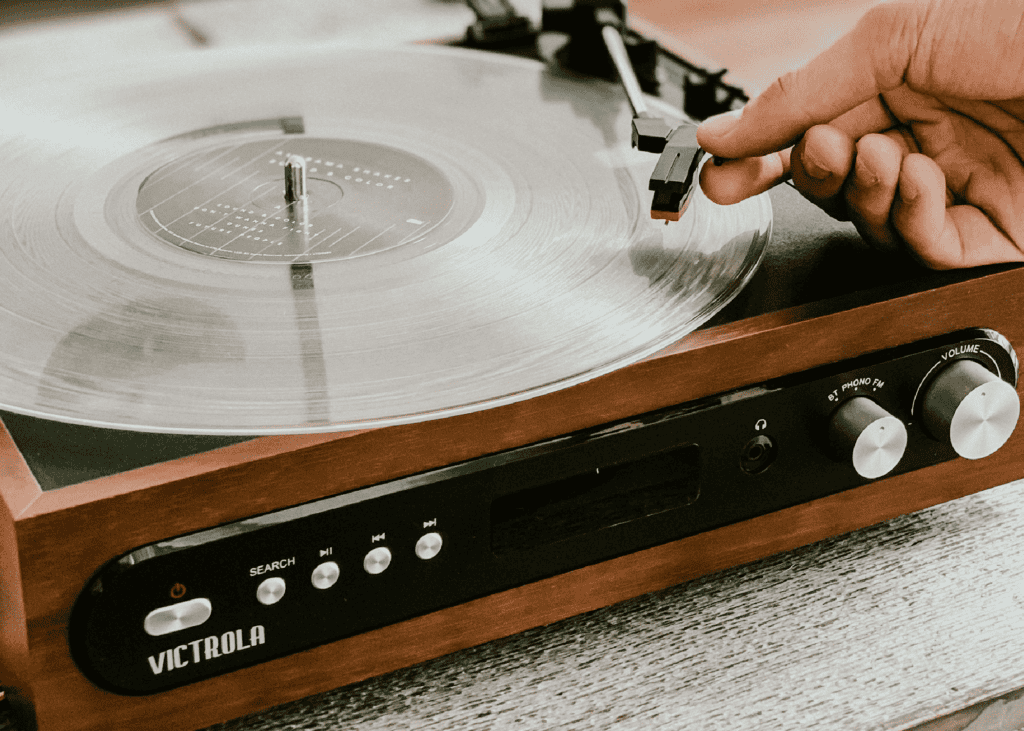 Hand moving a record pin onto record on a record player