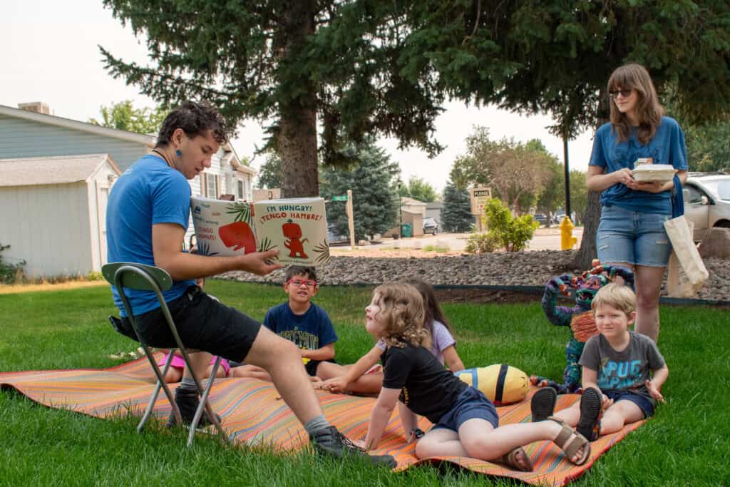 Empleada de la biblioteca leyendo un cuento a los niños al aire libre