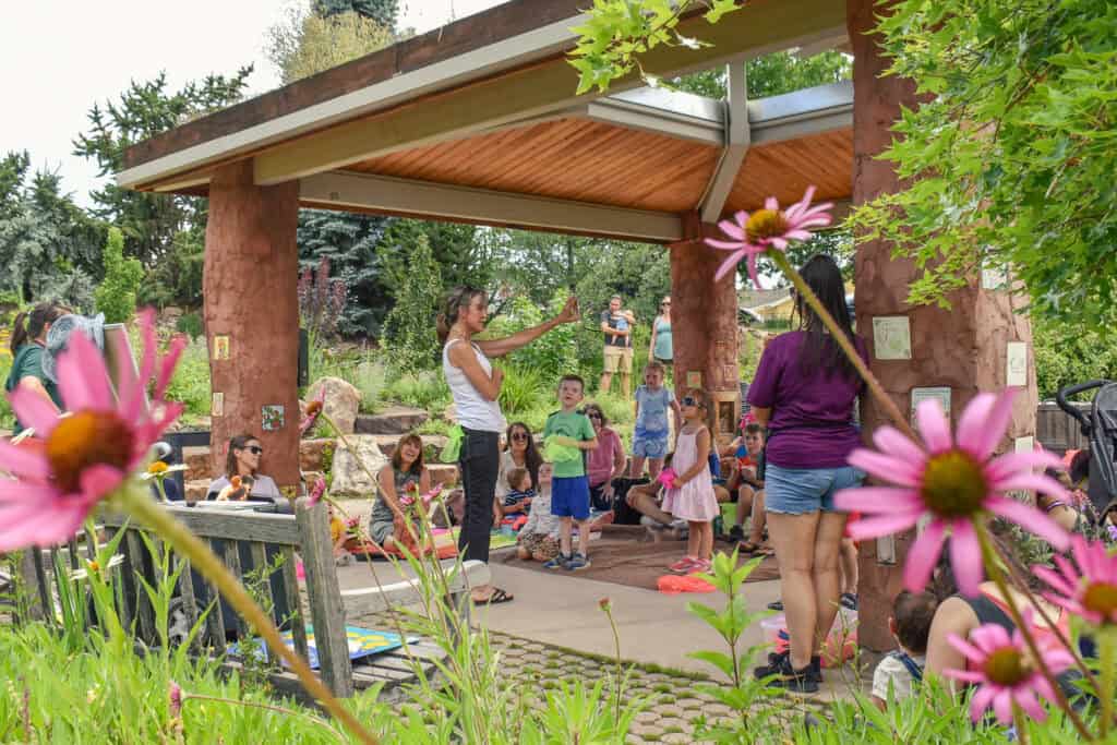 Una mujer lee un cuento a un grupo de niños durante una hora de cuentos en el jardín