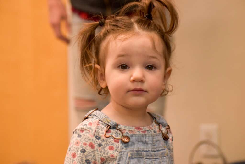 Niña mirando a la cámara para hacerse una foto en la biblioteca.