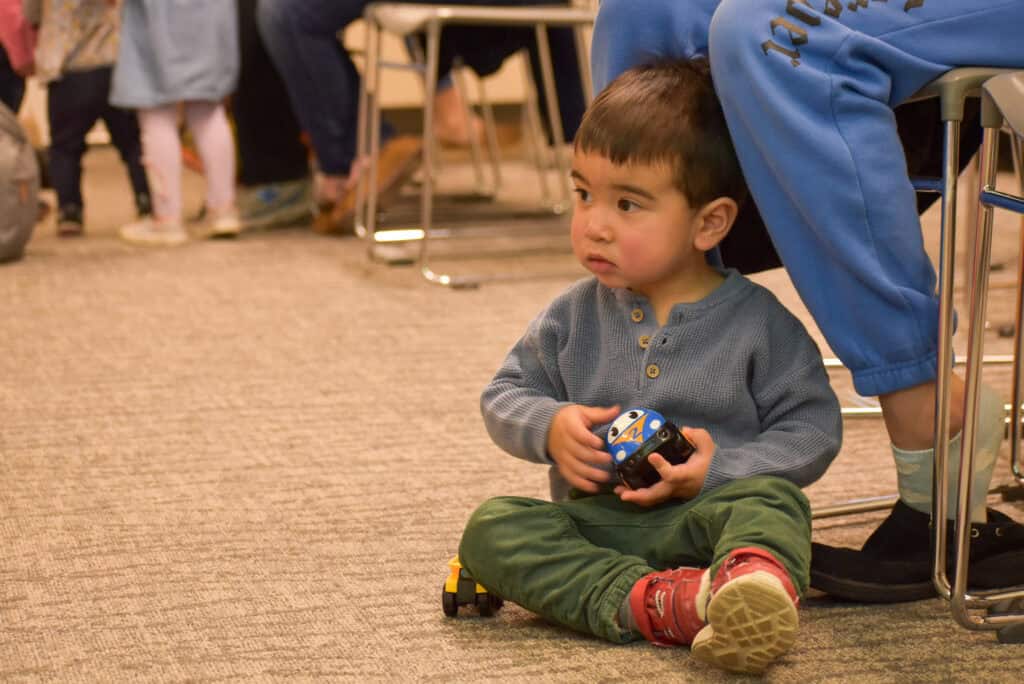 Un niño juega con un camión de juguete en la biblioteca.