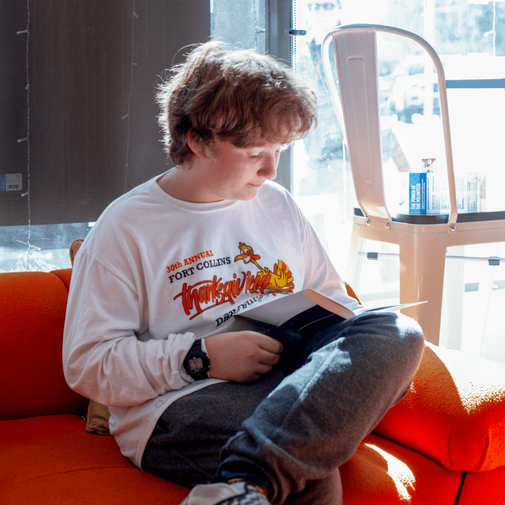 Teen boy sitting on couch reading a book