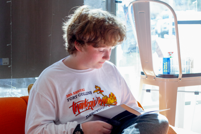 Teen boy sitting on couch reading a book