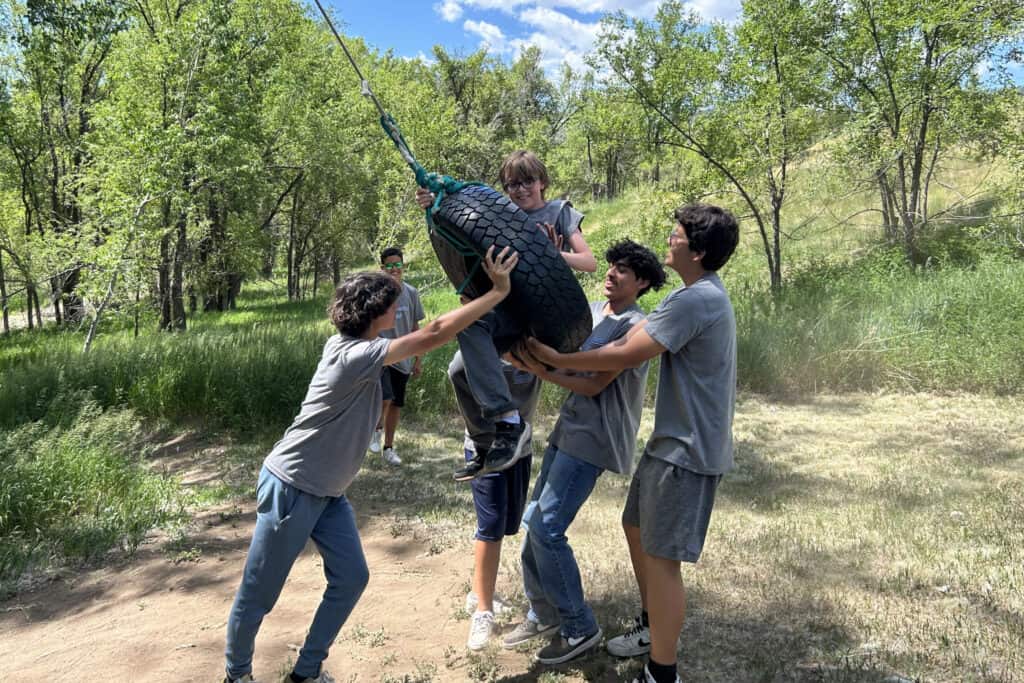 A group of teens using a tire swing outdoors