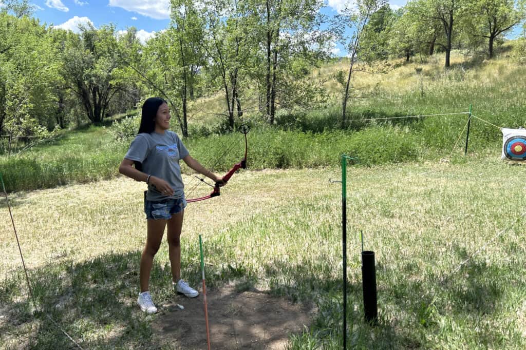 Teen girl shooting archery outside