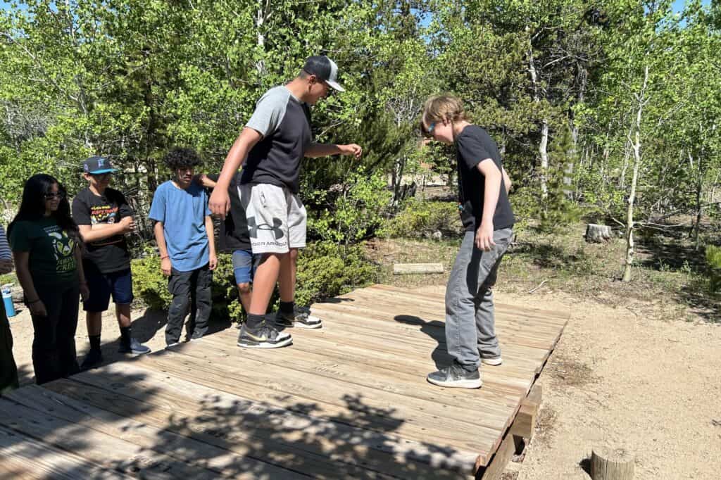 A group of teens playing outside on a wooden bridge