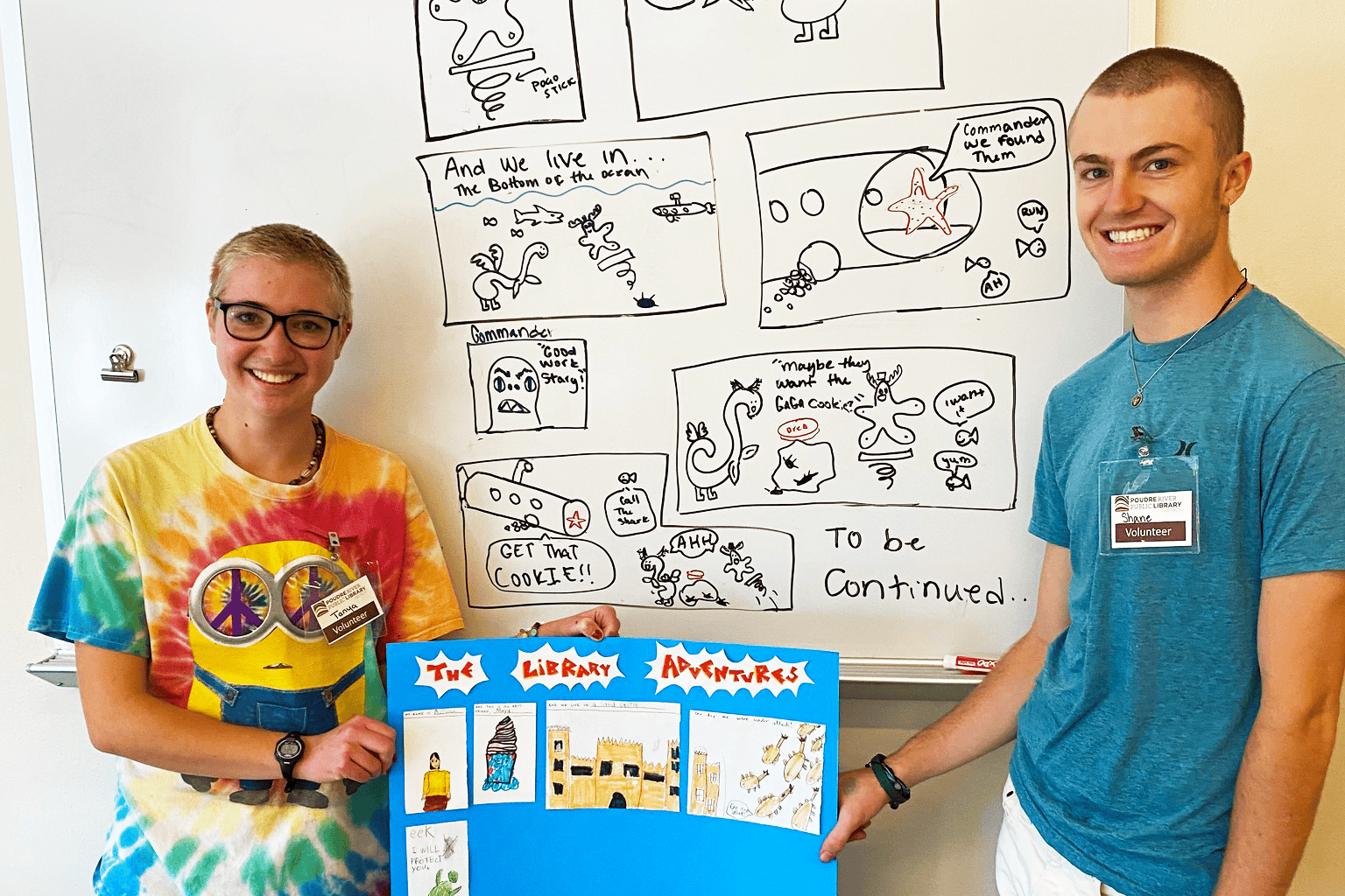 Two teenage volunteers with short hair holding a poster board