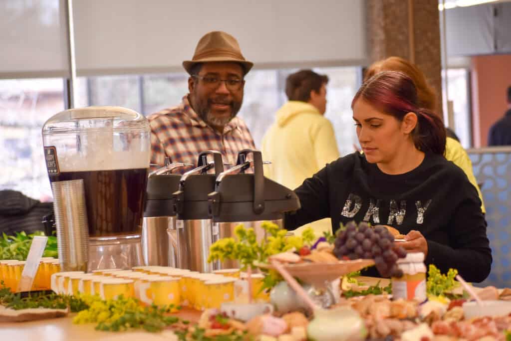 Woman filling up a plate at a buffet style table of food