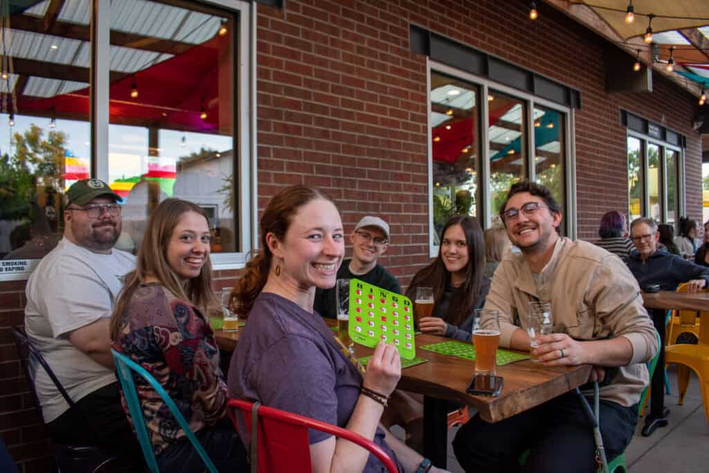 Group of young adults smiling for a photo and holding up bingo cards