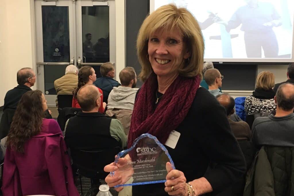 Woman smiling for a photo and holding an award