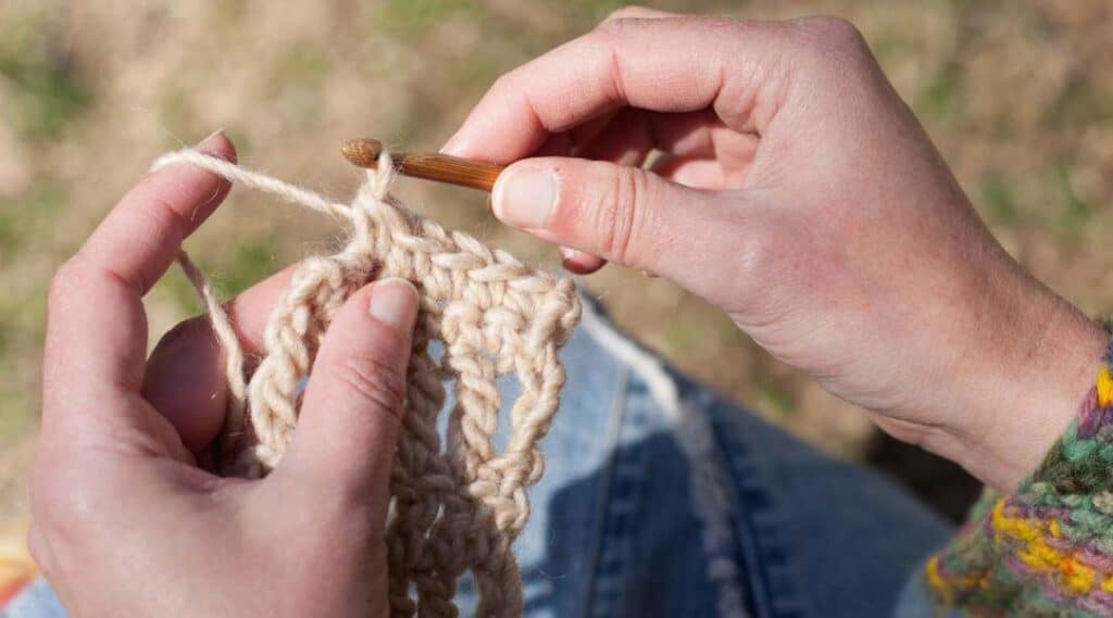 mujer haciendo ganchillo con un hilo de color crema