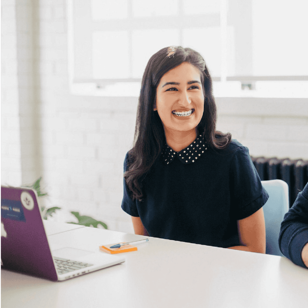 Woman with a laptop in front of her looking at someone not in the picture frame