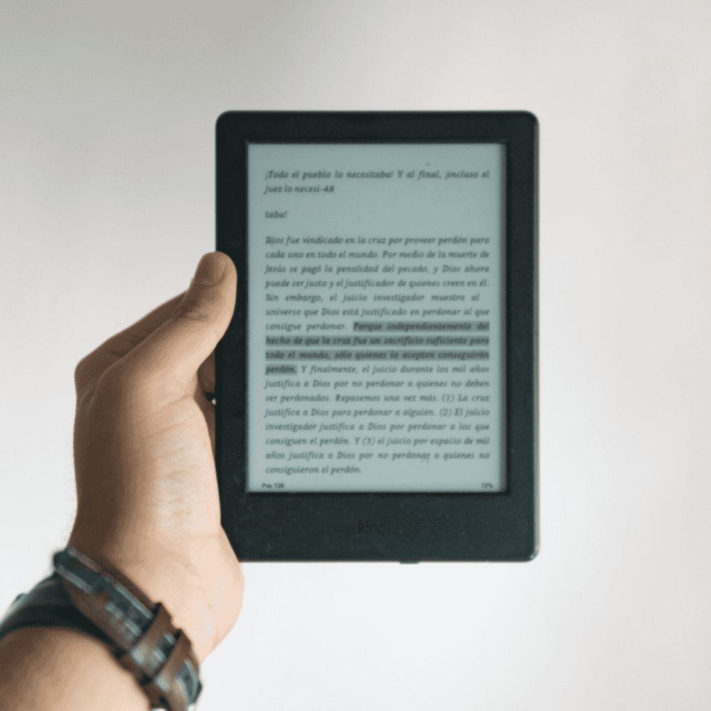 Hand holding up an eReader with a page of a book highlighted