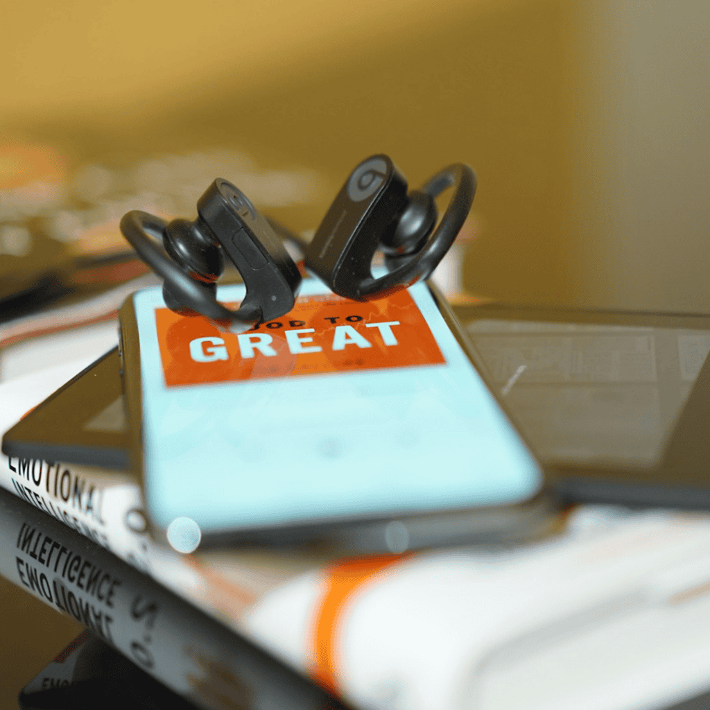 Phone screen showing an audiobook cover with headphones placed on top of the phone