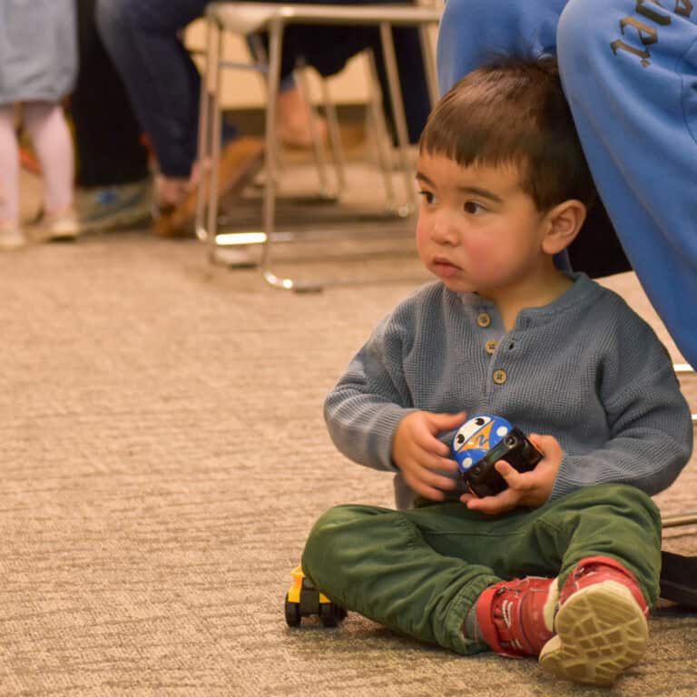 Young boy sitting on the ground and playing with a toy car