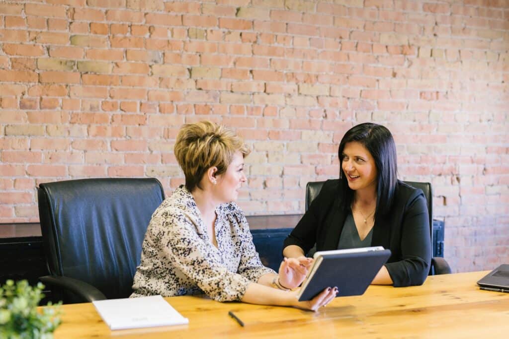 Dos mujeres hablando y sentadas en una mesa